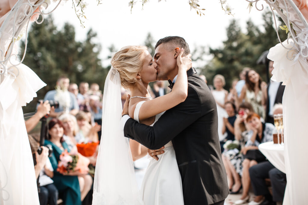 A bride and a groom are kissing in front of the guests in a wedding documentary film.