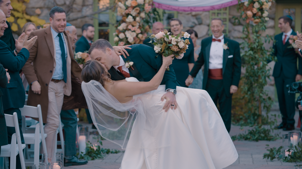 Humblebee Wedding Films, Willowdale Estate Topsfield Massachusetts, newly weds kiss, groom dips bride and the guests celebrate in the background