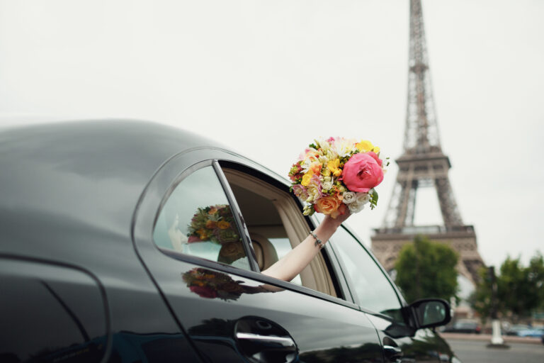 Humblebee Wedding Films Destination Wedding Videographer, Bride reaches out hand with wedding bouquet from a car before Eiffel Tower