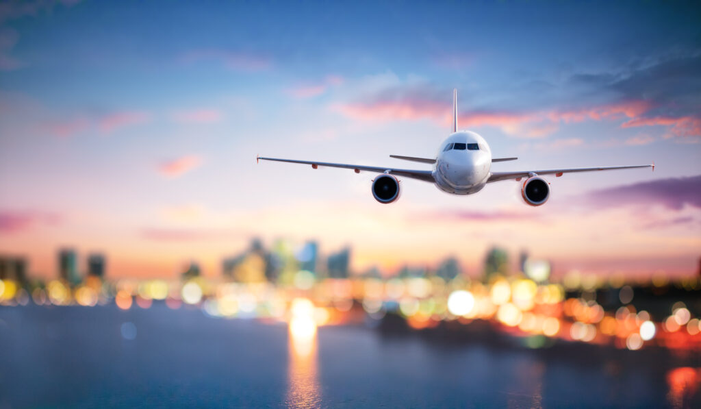 Humblebee Wedding Films Destination Wedding Videographer, white passenger jet flies through a sunset backed sky