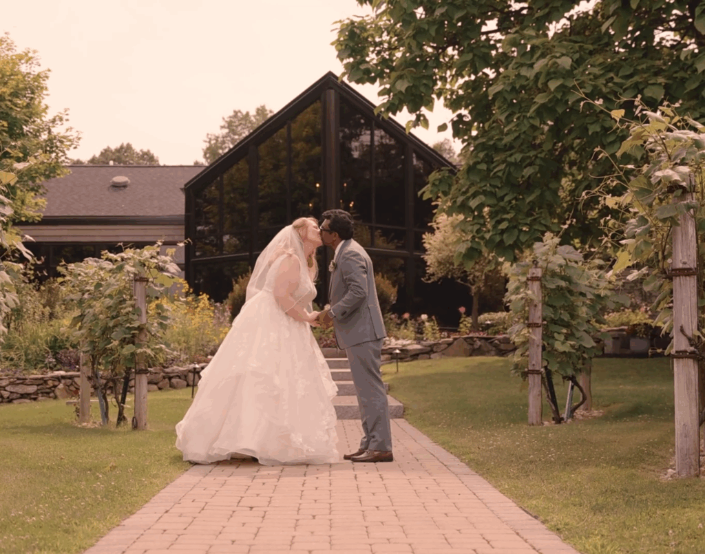 Humblebee Wedding Films Birch Wood Vineyards, newlyweds share a kiss before a large a-frame building before the reception