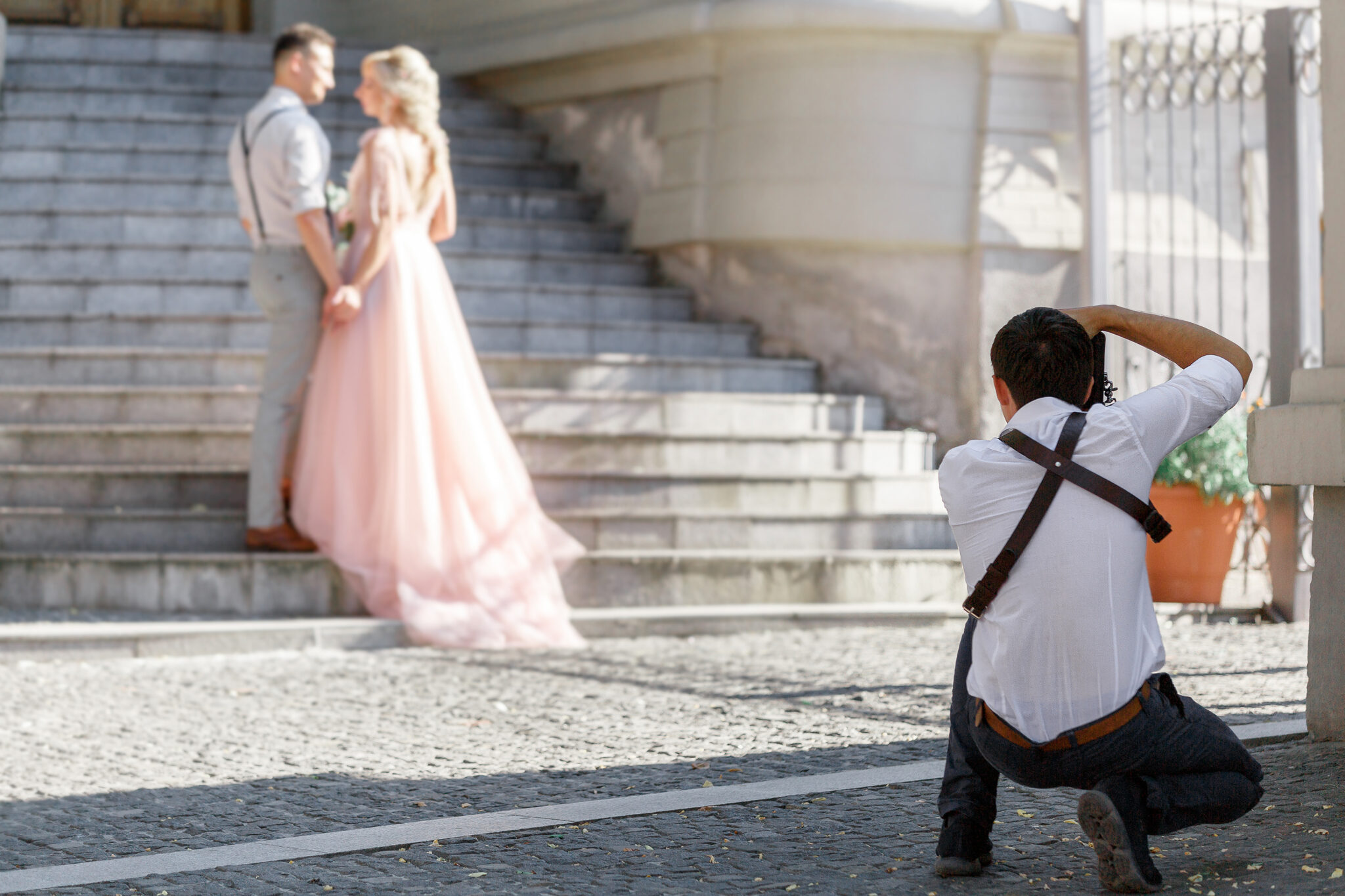 Humblebee Wedding Films Wedding Photography Styles, wedding photographer takes pictures of bride and groom in city. wedding couple on photo shoot. photographer in action