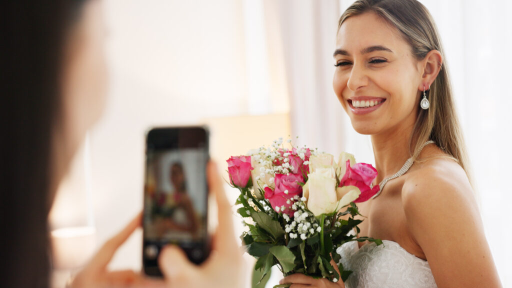 Humblebee Wedding Films Boston wedding content creator, Bride, bridesmaid and wedding picture with phone with flowers or bouquet, fashion dress and an excited smile for social media. Happy woman and friend with mobile smartphone before a marriage ceremony.