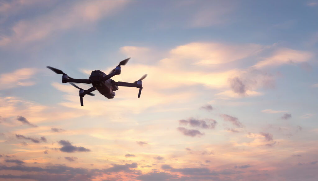 Humblebee Wedding drone wedding videographer, Close up of professional remote control drone flying against dramatic sunset sky background.