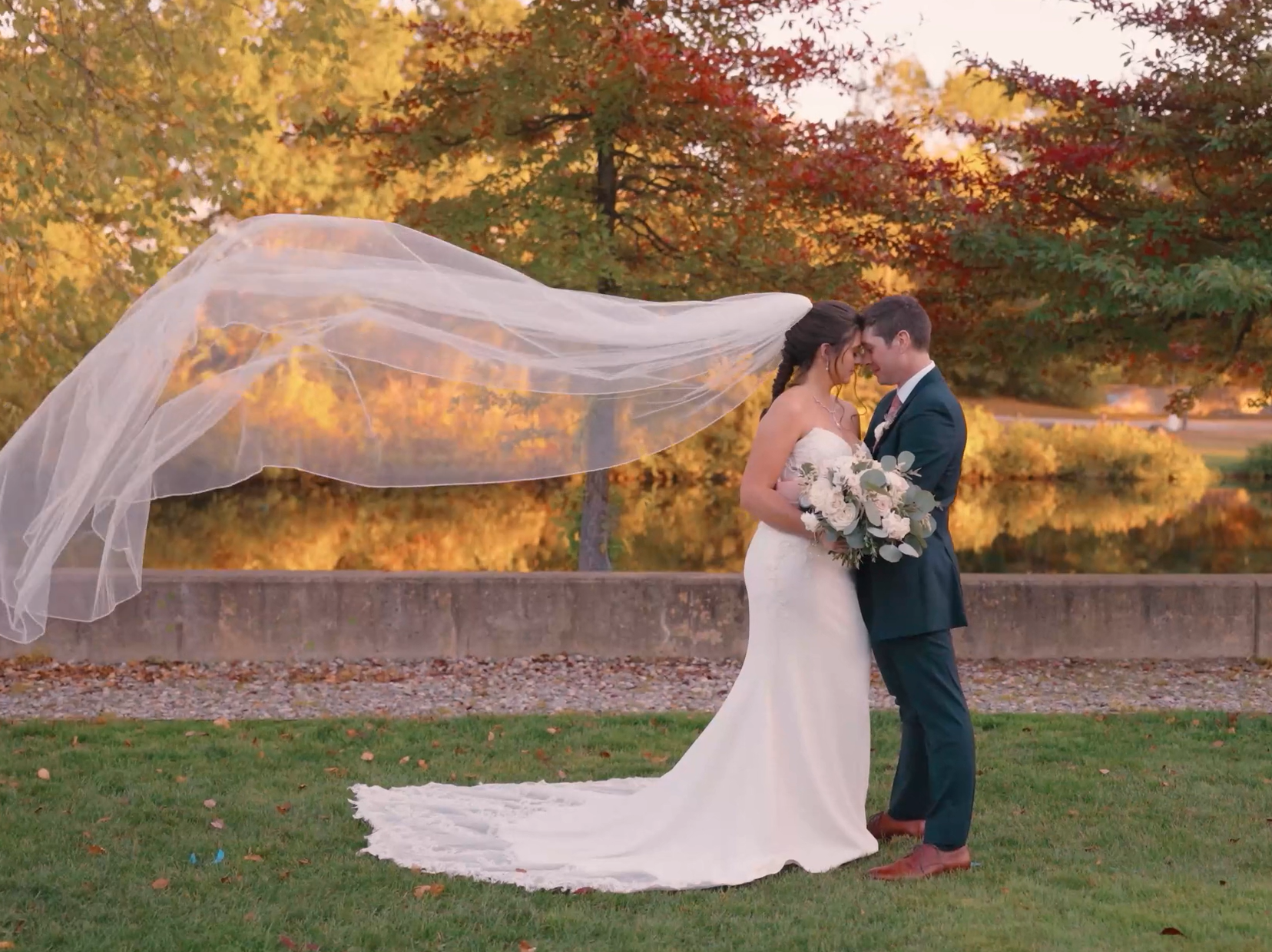 Humblebee Wedding Films Wedding Videographer, New Hampshire Wedding Videographers, newlyweds embrace before fall foliage with bride's veil flowing behind her