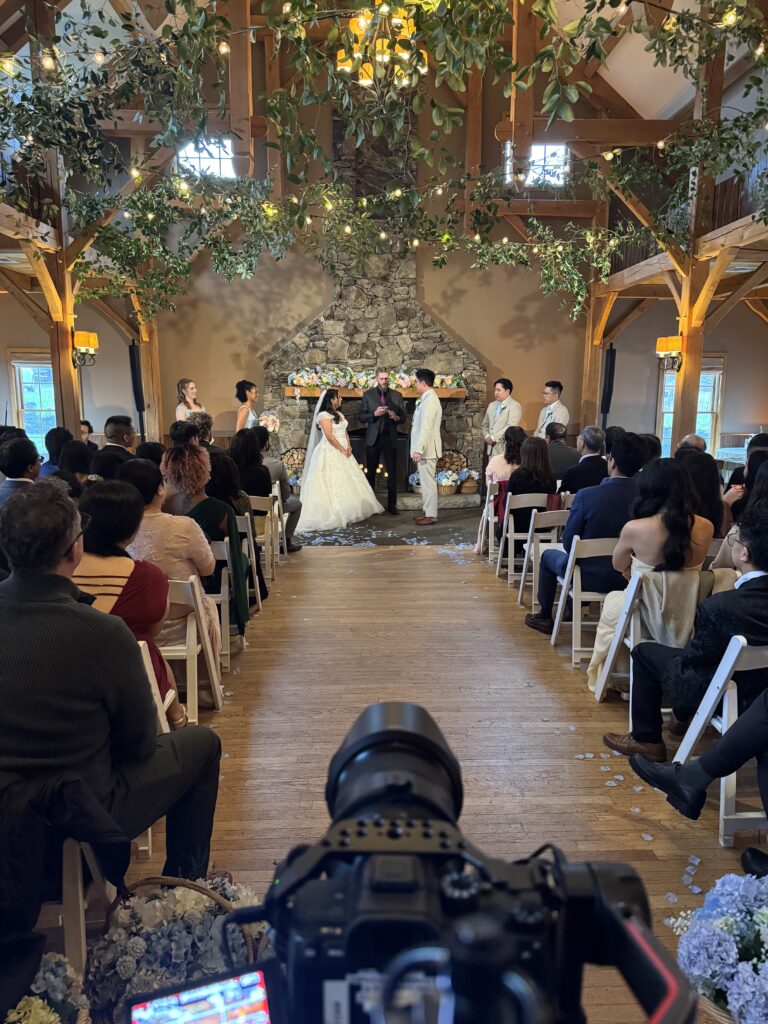 Surprising Fees for Wedding Videographers Near Me 6 Humblebee Wedding Films Videographers for Weddings Near me, a behind the scenes look at a wedding ceremony with natural wood beams, faux greenery, and fairy lights across the altar.